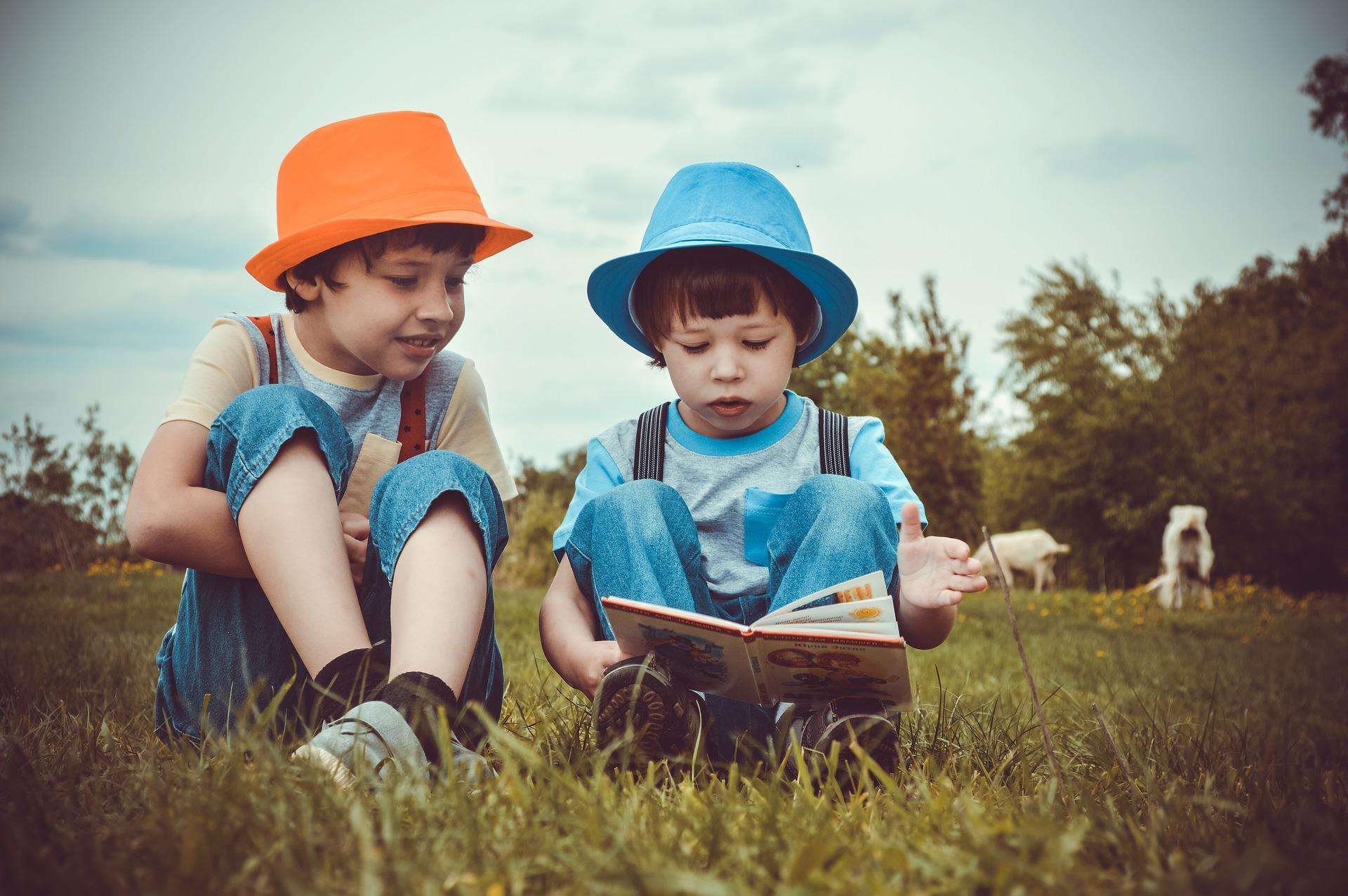 Two children read a book in a green field. electric vehicle charging options.
