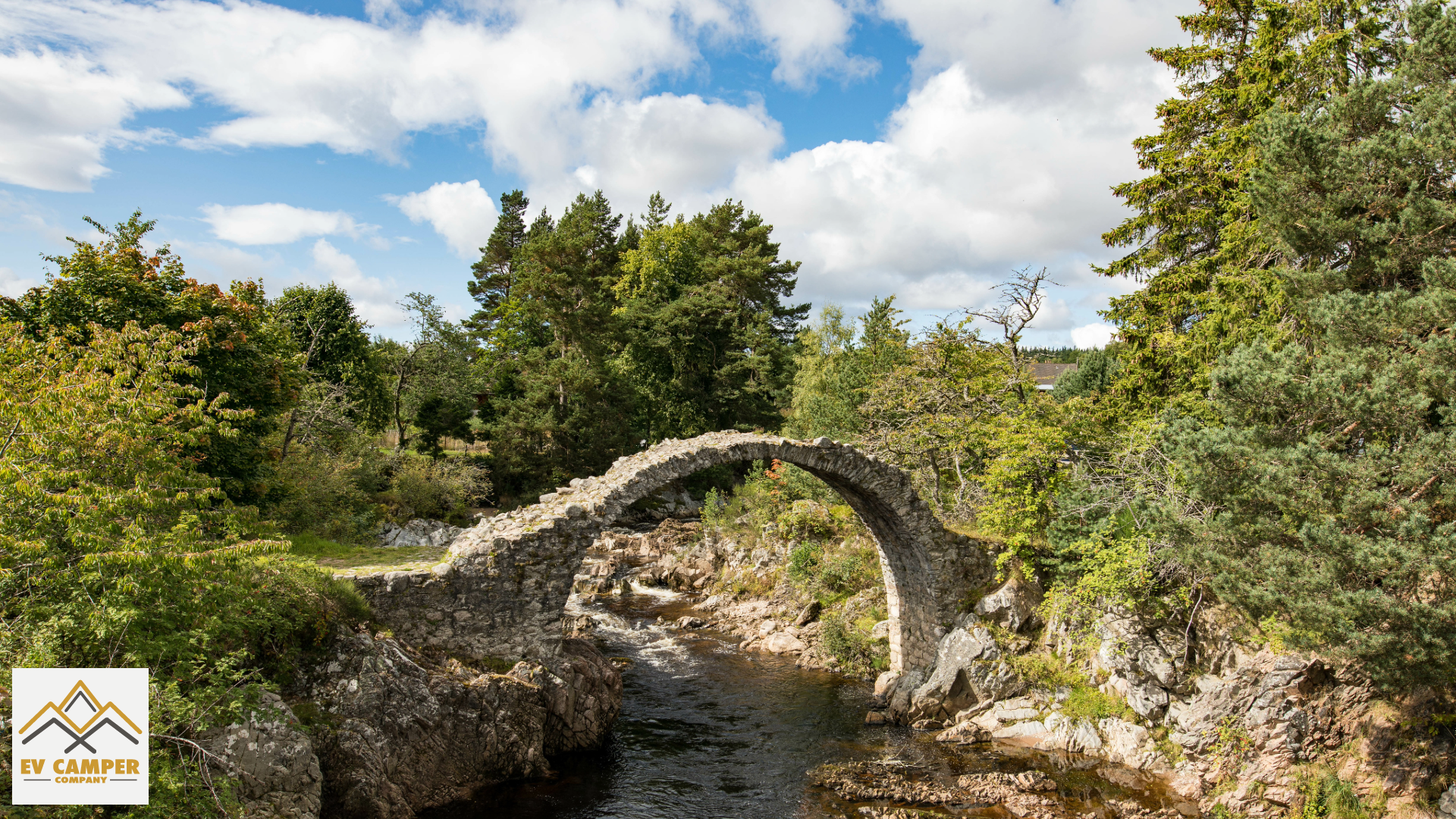 Ancient stone bridge arching over a rocky creek amidst dense Scottish woodlands, a picturesque and secluded camping site for romantic escapes.