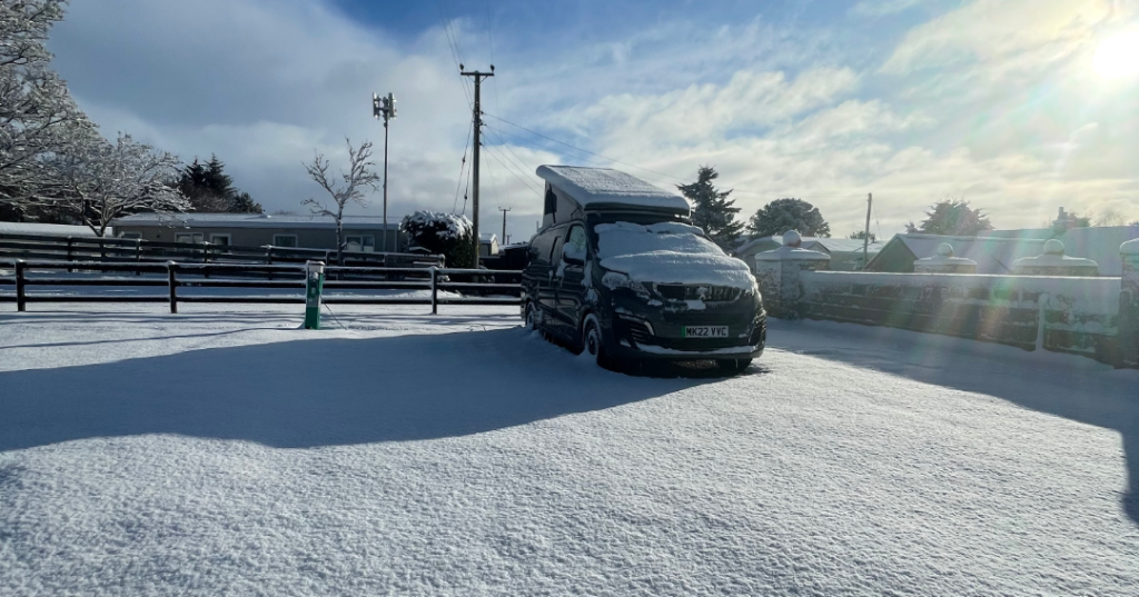 Winter camping in Scotland with a campervan parked amidst snowy Highland scenery.